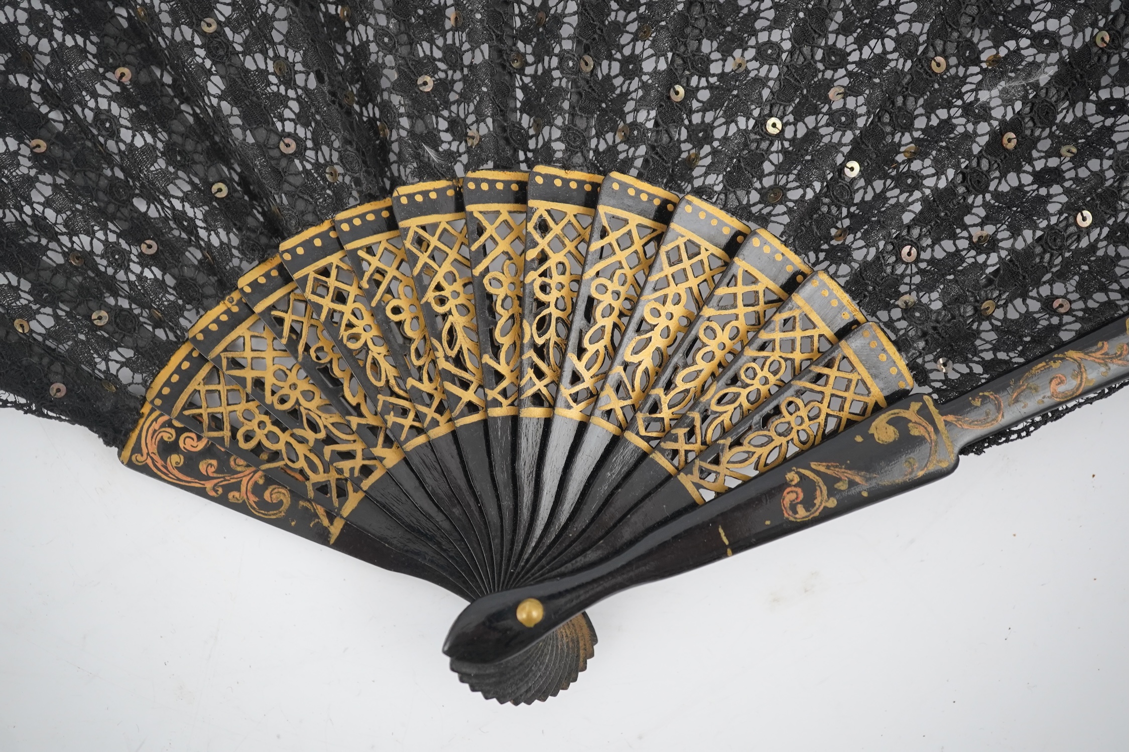 Three novelty fans with a mixed Brussels lace fan and black lace fan, a small language of love in flowers fan, a paper windmill advertising French Café fan, a carved cream Bakelite fan, a black and gilt, lace and sequin